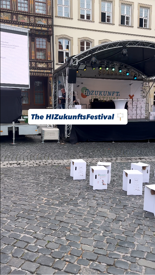 Stage setup for the HIZukunftsFestival with decorative boxes in a historic cobblestone square.