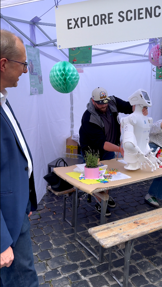 Visitor interacting with a robot at a science expo booth, showcasing innovative technology and exploration.