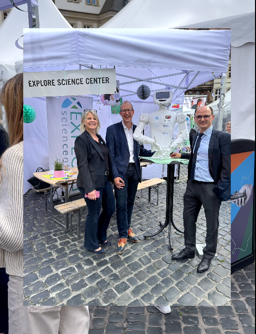 People at the Explore Science Center booth, showcasing interactive exhibits at an outdoor event.