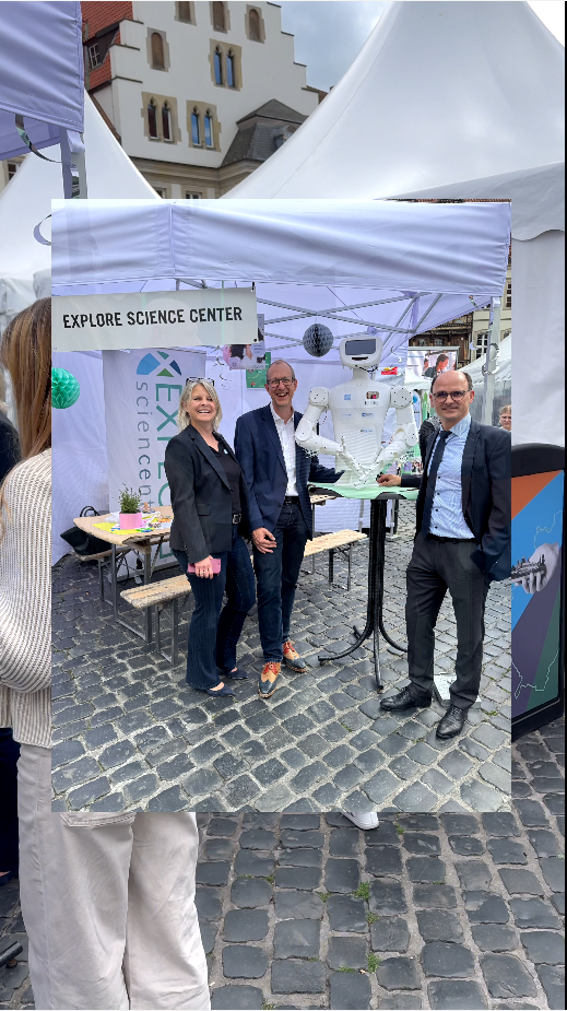 People at the Explore Science Center booth, showcasing interactive exhibits at an outdoor event.